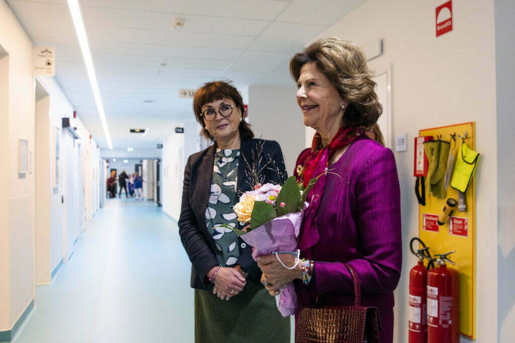 drottning silvia och sjukhusidrektör ann-marie wennberg står i en korridor och ser glada ut.