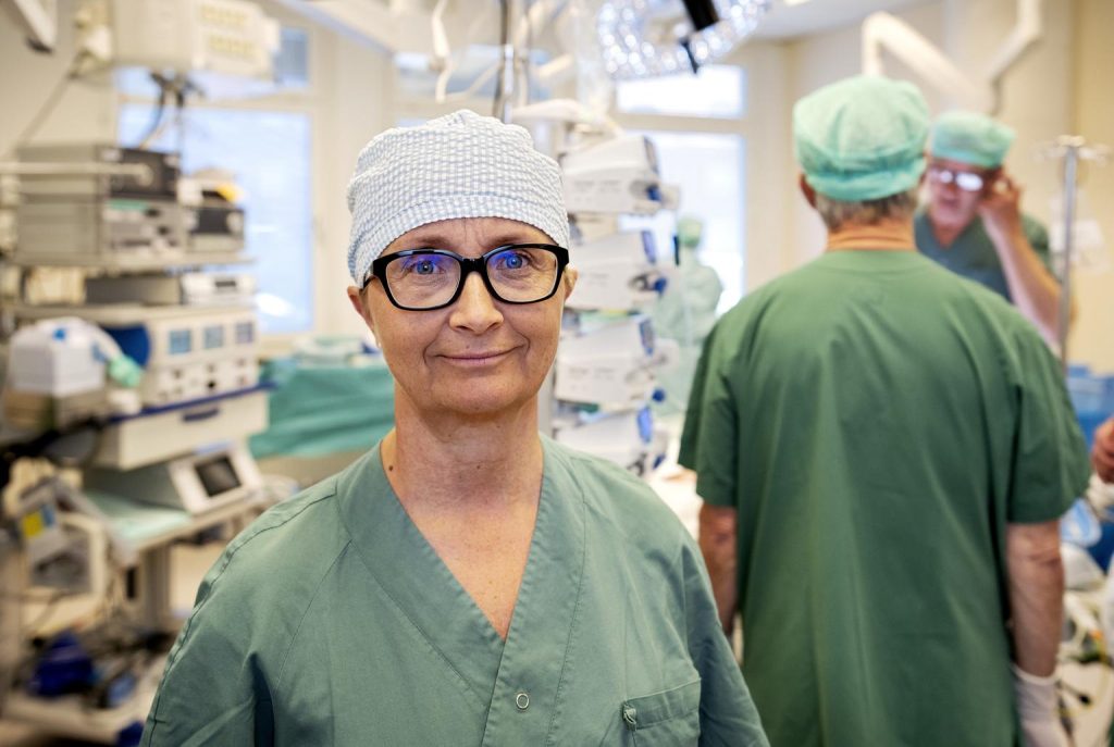 En kvinnlig kirurg i operationssalen, tittar in i kameran.